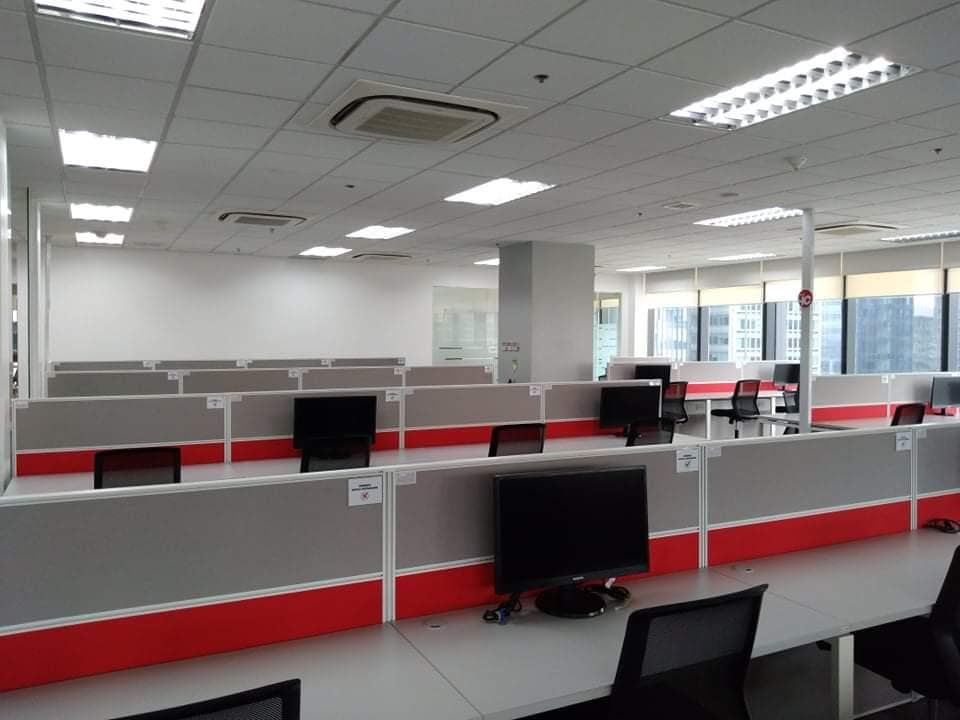 Open-plan workspace with desks facing city-view windows