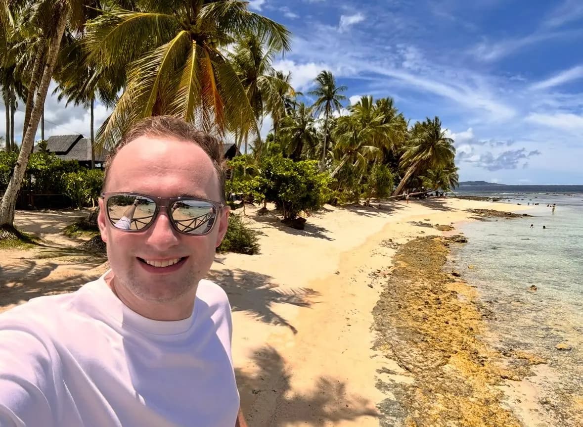 Adam on a palm-fringed beach on a weekend away